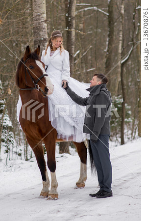 Groom Assisting Bride Dismounting Horse In Winter Groom Assisting Bride Dismounting Horse In Winter 136708761
