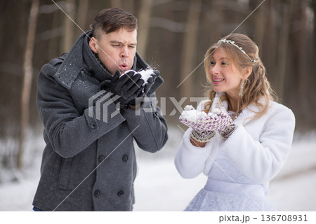Groom Blowing Snow While Bride Smiles Happily Groom Blowing Snow While Bride Smiles Happily 136708931