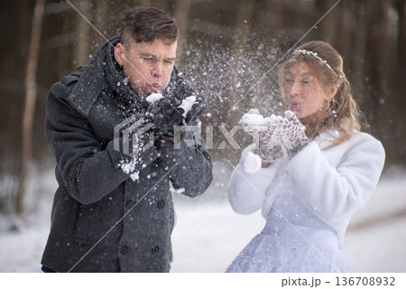 Playful Wedding Couple Blowing Snow Mid Air Playful Wedding Couple Blowing Snow Mid Air 136708932