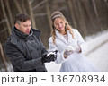 Bride and Groom Examining Snow In Gloves 136708934