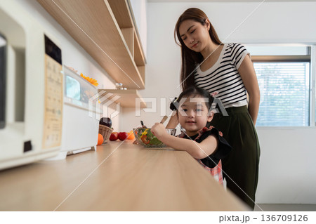 A woman is feeding a young girl a salad 136709126