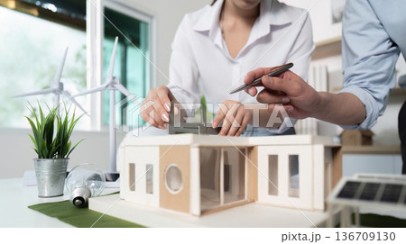 A woman and a man are working on a model of a house 136709130