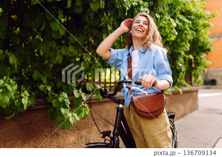 Beautiful woman riding bicycle at the city street outdoor. Active lifestyle. Eco transport. 136709134