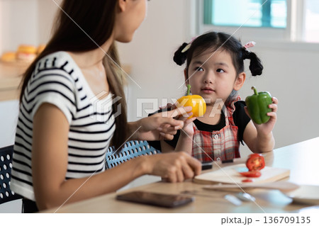 A woman is teaching a young girl about vegetables 136709135
