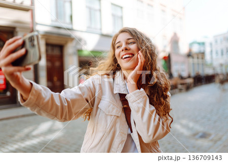 Lifestyle selfie portrait of young positive woman having fun and taking selfie in city. Active life. Lifestyle selfie portrait of young positive woman having fun and taking selfie in city. Active life. 136709143