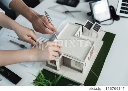 Two people are working on a model of a house Two people are working on a model of a house 136709145
