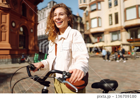 Beautiful woman riding bicycle at the city street outdoor. Active lifestyle. Eco transport. 136709180