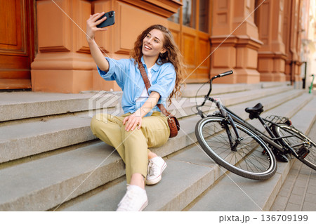 Woman using mobile phone while walks with a bicycle. Selfie time. People, blogging and lifestyle. 136709199