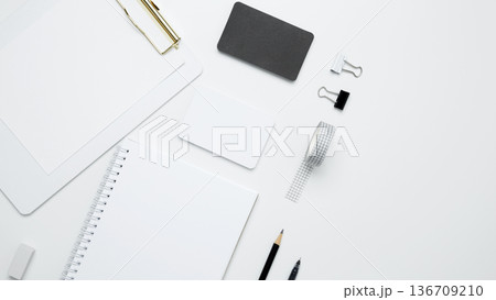 On a white background, an empty mock up notebook and clipboard, white and black cards. Monochrome stationery items 136709210