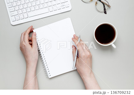 Woman writing on  notebook at organized workspace with stationery items 136709232