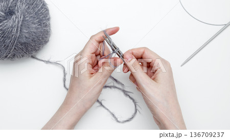 Woman crafting textile by hand using knitting needles 136709237