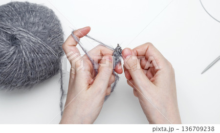 Woman knitting by hand using needles to create a cozy handmade textile Woman knitting by hand using needles to create a cozy handmade textile 136709238