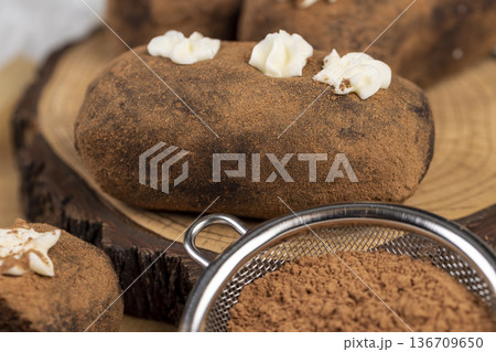 sweet brown pastry potatoes are lying on a serving board and paper, sweet classic cake from butter and a large amount of cocoa mixed with sponge cake and cognac, cocoa powder sweet brown pastry potatoes are lying on a serving board and paper, sweet classic cake from butter and a large amount of cocoa mixed with sponge cake and cognac, cocoa powder 136709650