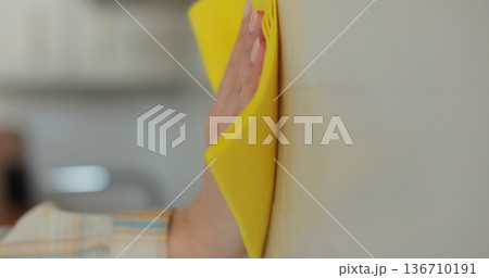 Woman cleaning the kitchen wall. Cleaning, hands and spray bottle with person in kitchen of home for chores, housework or hygiene. 136710191