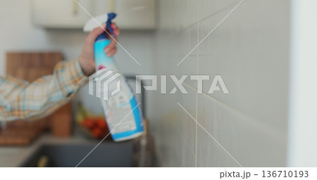 Woman cleaning the kitchen wall. Cleaning, hands and spray bottle with person in kitchen of home for chores, housework or hygiene. 136710193