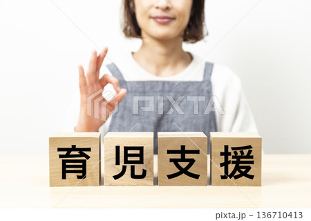 「育児支援」と書かれたブロックとエプロン姿の女性 「育児支援」と書かれたブロックとエプロン姿の女性 136710413
