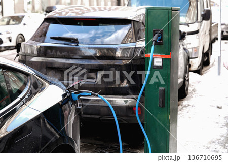 Electric car charging at public station in winter Electric car charging at public station in winter 136710695