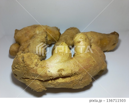Fresh ginger root resting on a clean white surface. Fresh ginger root resting on a clean white surface. 136711503