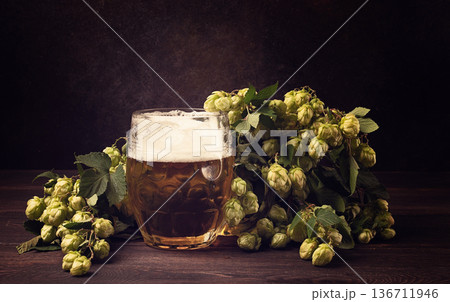 A mug of beer , on a wooden table, with a branch of fresh hops, rustic , no people, A mug of beer , on a wooden table, with a branch of fresh hops, rustic , no people, 136711946