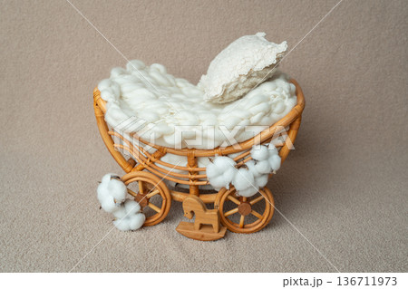 Small handmade rattan pram with soft white bedding. Styled newborn photography prop in neutral beige tones. Perfect for baby studio sessions and minimal lifestyle concepts. Small handmade rattan pram with soft white bedding. Styled newborn photography prop in neutral beige tones. Perfect for baby studio sessions and minimal lifestyle concepts. 136711973