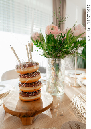Creative donut tower as alternative birthday cake. Stylish festive table setup with flowers and candles, ideal for party planning, celebration and lifestyle branding concepts. Creative donut tower as alternative birthday cake. Stylish festive table setup with flowers and candles, ideal for party planning, celebration and lifestyle branding concepts. 136711977