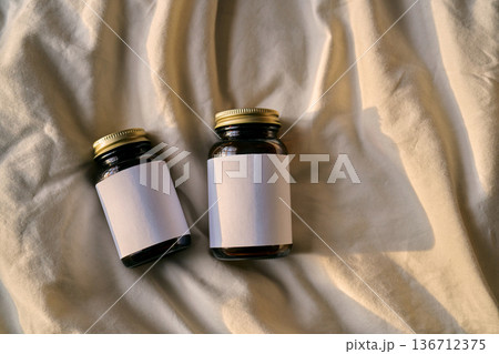 Blank amber glass supplement bottles on beige fabric 136712375
