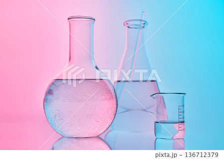 Chemistry laboratory glassware with liquid and pink blue background Chemistry laboratory glassware with liquid and pink blue background 136712379