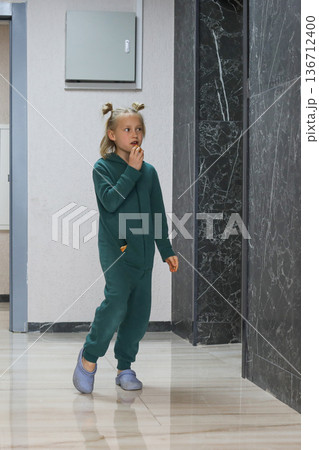 Healthy little girl wearing green jumpsuit standing in lobby lounge. Adorable child 6 years old Healthy little girl wearing green jumpsuit standing in lobby lounge. Adorable child 6 years old 136712400