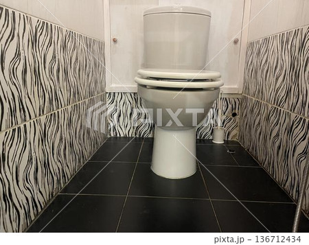 the toilet in the restroom with light from a lamp lighting 136712434