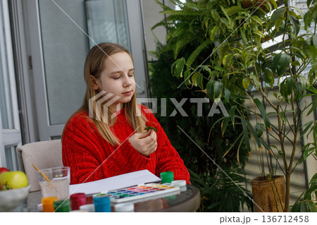 Portrait of young girl eating red strawberry and sitting on a balcony. Preteen child Portrait of young girl eating red strawberry and sitting on a balcony. Preteen child 136712458
