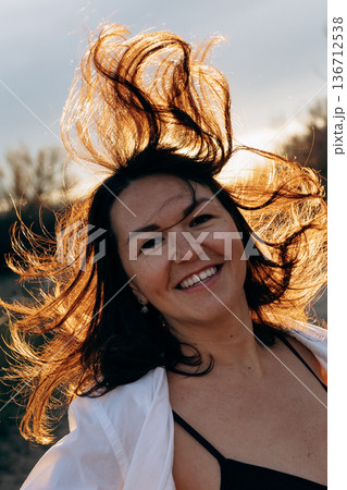 Cheerful Woman with Wind-Swept Hair Outdoors 136712538
