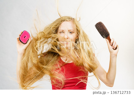 Blonde girl long blowing hair holds two brushes Blonde girl long blowing hair holds two brushes 136712733