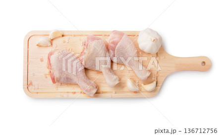 Top view of three raw chicken drumsticks on a wooden board with garlic and salt, isolated on a white background. Fresh poultry meat ready for cooking. High quality photo Top view of three raw chicken drumsticks on a wooden board with garlic and salt, isolated on a white background. Fresh poultry meat ready for cooking. High quality photo 136712756
