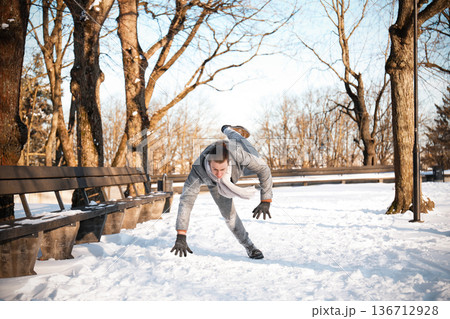 A man in a coat slips and falls on a snowy, icy path in a park, illustrating the dangers of slippery winter conditions, winter injuries, and the need for health insurance. High quality photo A man in a coat slips and falls on a snowy, icy path in a park, illustrating the dangers of slippery winter conditions, winter injuries, and the need for health insurance. High quality photo 136712928