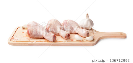 Raw chicken drumsticks on a wooden cutting board with garlic and pink salt isolated on white background. Fresh poultry meat ready for cooking. High quality photo Raw chicken drumsticks on a wooden cutting board with garlic and pink salt isolated on white background. Fresh poultry meat ready for cooking. High quality photo 136712992