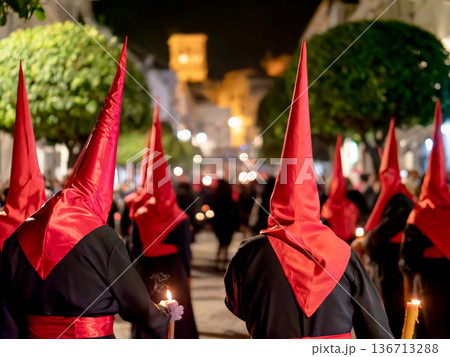 Many nazarenos with red hoods walking in procession Many nazarenos with red hoods walking in procession 136713288
