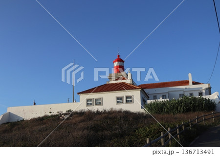Red lighthouse tower and traditional white buildings at Cabo da Roca, Portugal. 136713491