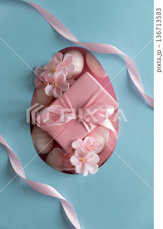 Easter Gift Box with Decorated Eggs and Blossoms in Heart Cutout. Festive Spring Flatlay on Blue Background Easter Gift Box with Decorated Eggs and Blossoms in Heart Cutout. Festive Spring Flatlay on Blue Background 136713583
