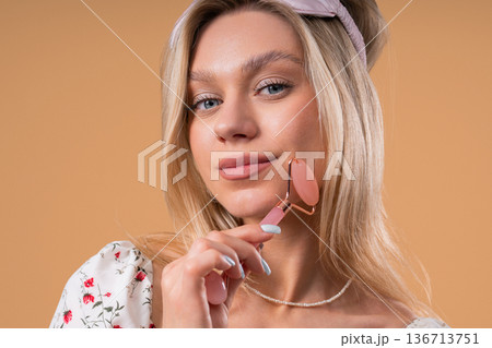 Charming Woman Doing Face Massage With Rose Quartz Stone Roller For Firmer 136713751