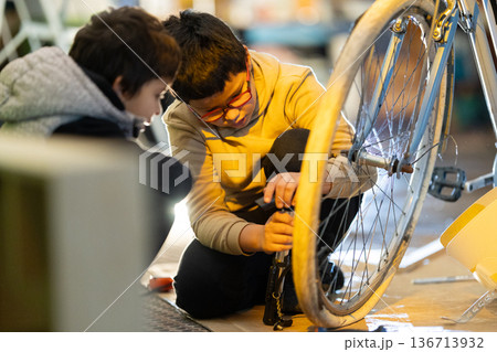 Boys learning bicycle repair and maintenance in workshop 136713932