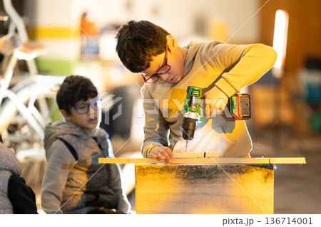 Child developing practical skills using power drill Child developing practical skills using power drill 136714001