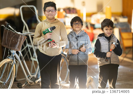 Three boys proudly holding hand tools in workshop Three boys proudly holding hand tools in workshop 136714005