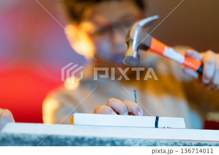 Person hammering nail into wood plank, focused on diy project 136714011