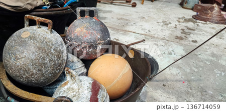 A top view of vintage metal weights on a distressed concrete floor. Concept of storage, recycling, flea market finds, and sports A top view of vintage metal weights on a distressed concrete floor. Concept of storage, recycling, flea market finds, and sports 136714059
