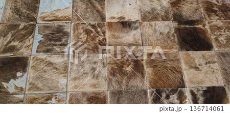 A rug made of square cowhide leather patches in shades of brown and beige. Concept: natural materials, eco-friendly decor, country style, textured background, rustic interior design A rug made of square cowhide leather patches in shades of brown and beige. Concept: natural materials, eco-friendly decor, country style, textured background, rustic interior design 136714061
