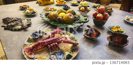 Handicrafts ceramic fruits, vegetables, seafood, and breads displayed on decorative plates and platters. Concept: traditional markets, handicrafts, interior design, artisan craftsmanship. Handicrafts ceramic fruits, vegetables, seafood, and breads displayed on decorative plates and platters. Concept: traditional markets, handicrafts, interior design, artisan craftsmanship. 136714065