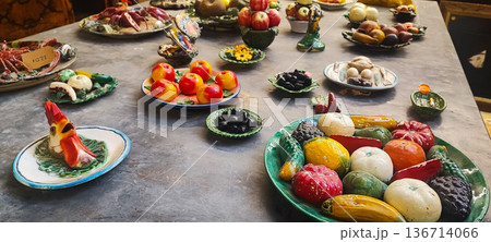 Handicrafts ceramic fruits, vegetables, seafood, and breads displayed on decorative plates and platters. Concept: traditional markets, handicrafts, interior design, artisan craftsmanship. Handicrafts ceramic fruits, vegetables, seafood, and breads displayed on decorative plates and platters. Concept: traditional markets, handicrafts, interior design, artisan craftsmanship. 136714066