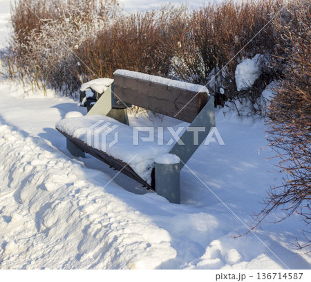A park bench covered in snow during winter A park bench covered in snow during winter 136714587