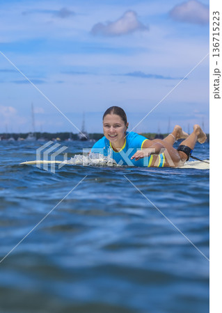 Woman Paddles Across Tiny Ocean Surf During Sunny Summer Day Woman Paddles Across Tiny Ocean Surf During Sunny Summer Day 136715223