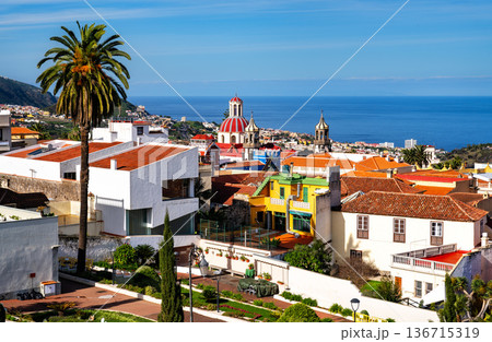 View of the historic town of La Orotava and the Church of La Concepcion in Tenerife, Canary Islands, Spain. Features colorful houses, palm trees, and the Atlantic Ocean. 136715319
